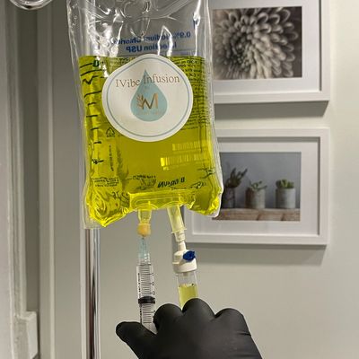 IV bag with yellow liquid held by a gloved hand.