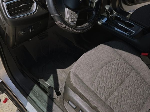Front interior of a car with a gray fabric seat and steering wheel.