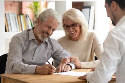 Elderly couple signing documents with a consultant.