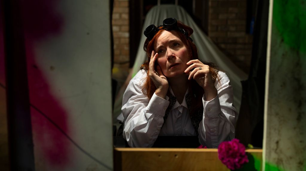 Woman in white shirt with goggles looks thoughtful and worried.