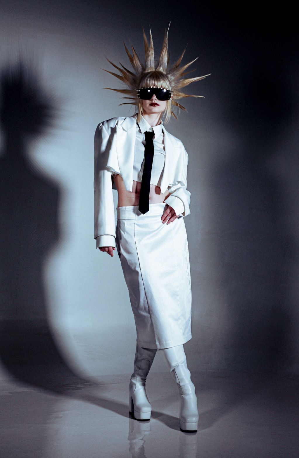 Woman in avant-garde white outfit with spiked hair and large sunglasses.