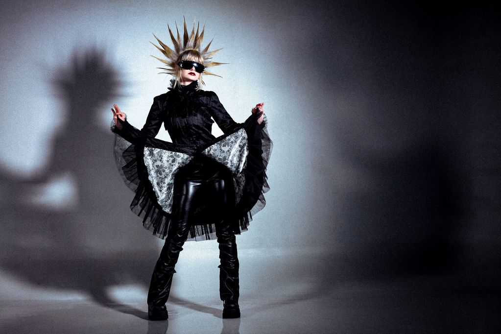 Person in black gothic outfit with spiked hair and sunglasses.