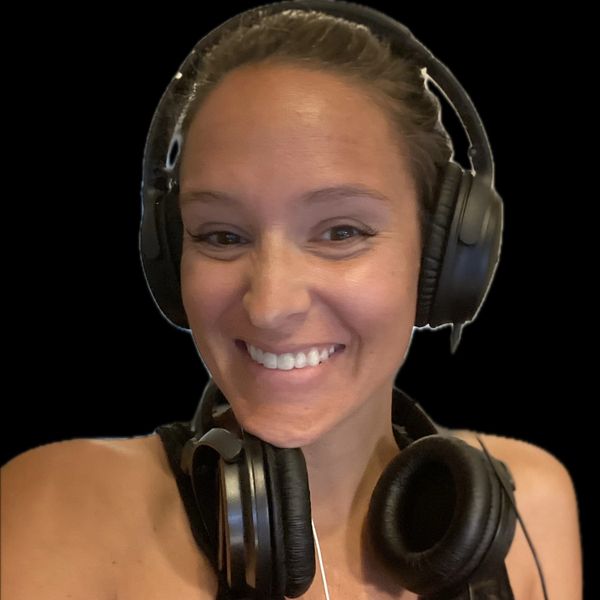 Smiling woman wearing two pairs of headphones.