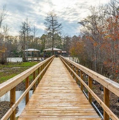 Wooden boardwalk leading to covered picnic areas in a serene natural setting.