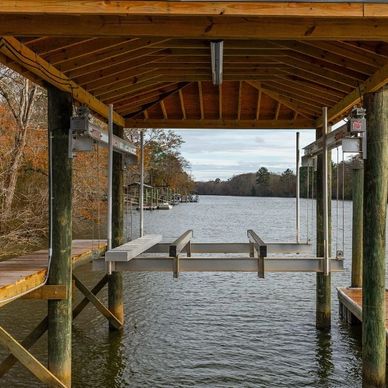 Covered wooden boat dock overlooking a calm river with autumn trees.