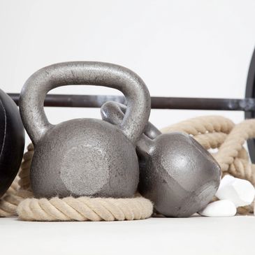 Kettlebells, dumbbell, and climbing rope for workout.