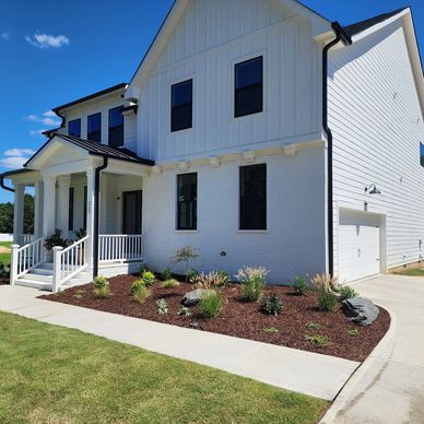 Modern white two-story house with neat landscaping.