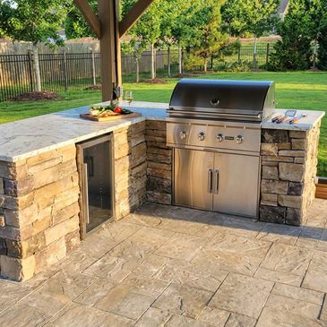 Modern outdoor kitchen with stainless steel grill and stone counter.