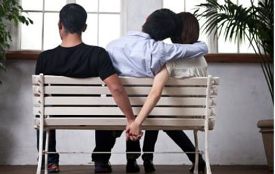 3 people sat on a bench facing away. The outer 2 people covertly hold hands behind  the bench.