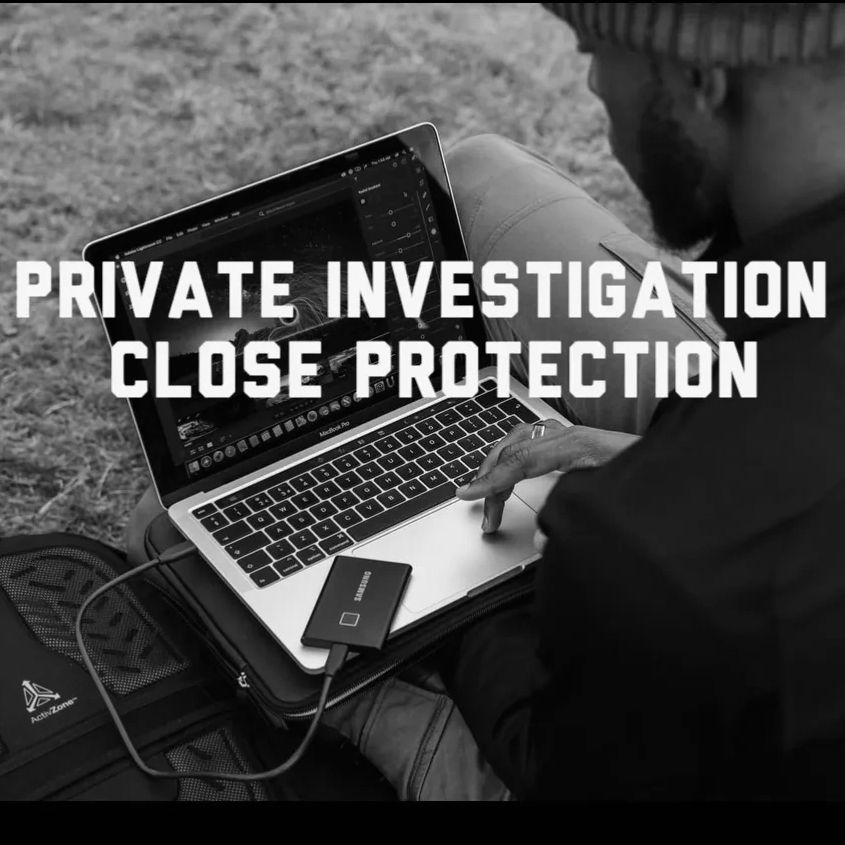 A man with a laptop conducting private investigation work whilst sitting on the grass.