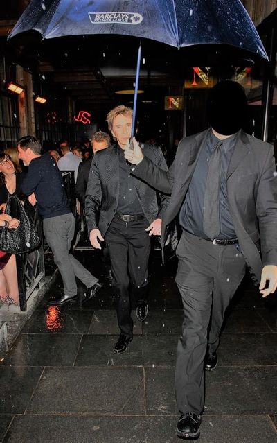 A close protection officer holding a umbrella for Barry Manilow during a close protection operation.