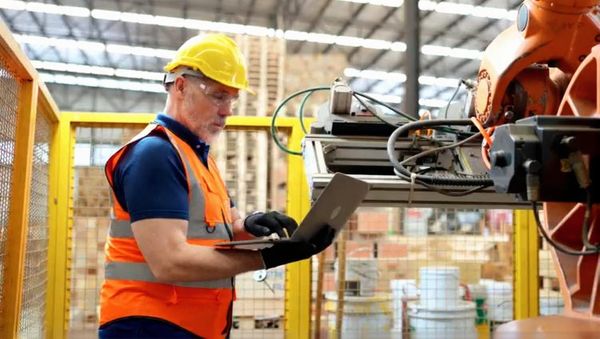 Technician maintaining large orange machinery.