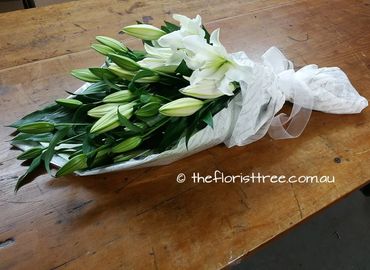 A  hand tied funeral sheaf of white lily flowers created by a qualified florist at The Florist Tree