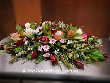 Mixed native and hothouse flowers in a funeral  casket spray  by a qualified florist 