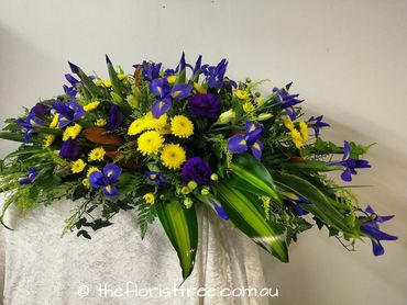 Yellow and purple funeral casket flowers created by a qualified florist at The Florist Tree