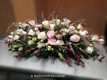 Pretty pastel funeral casket flowers created by a qualified florist at The Florist Tree