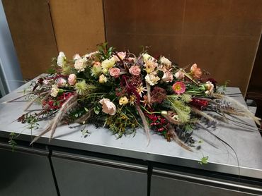Whimsical funeral casket flowers created by a qualified florist at The Florist Tree