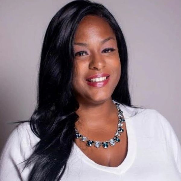 Smiling woman with long black hair and a statement necklace.