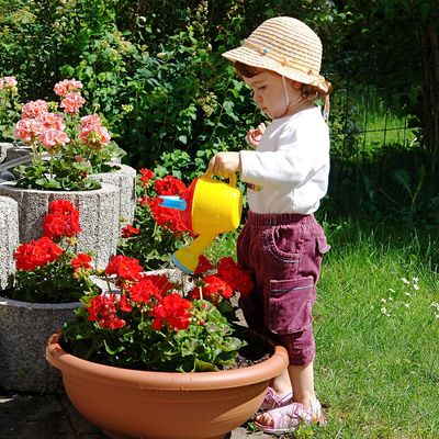 Girl watering flowers with a plastic watering can