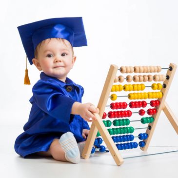Toddler sitting at an abacus wearing a cap and gown