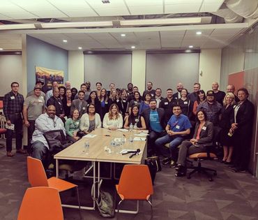 group shot containing about 30 adults posing for a picture in conference room