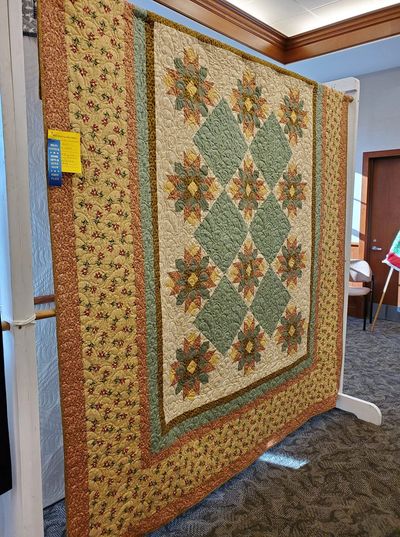 Award-winning floral quilt with geometric patterns in earth tones.