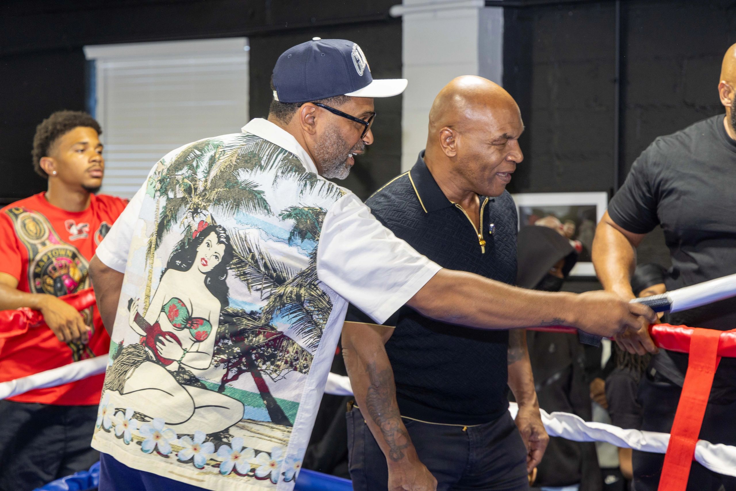 Men talking inside a boxing ring.