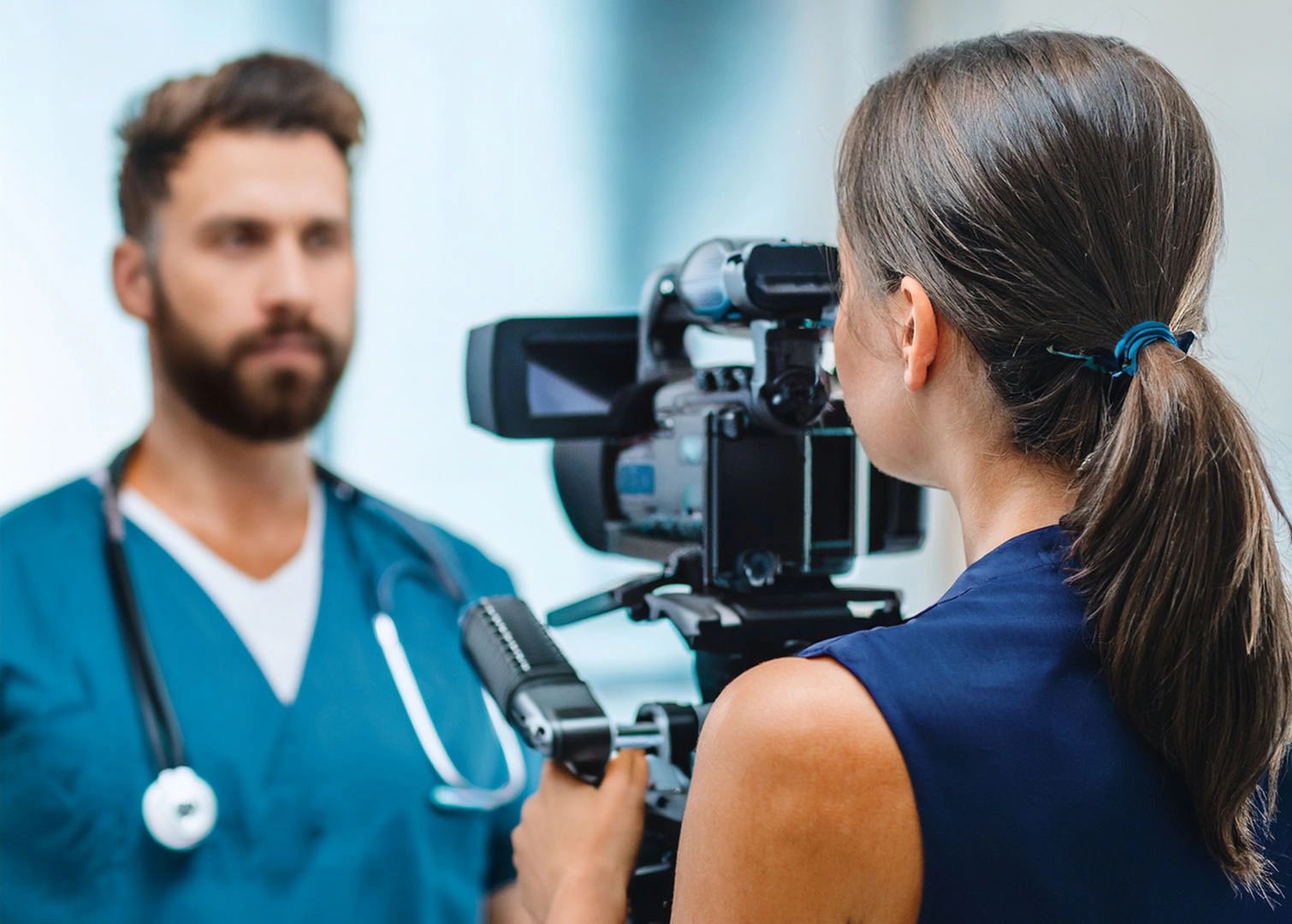 A female camerawoman filming a male doctor.