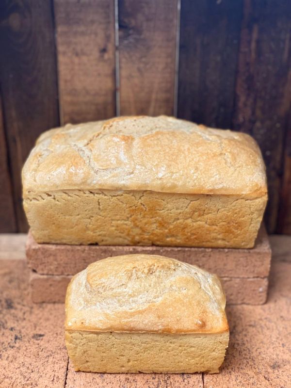 Two fresh loaves of bread on a rustic surface.