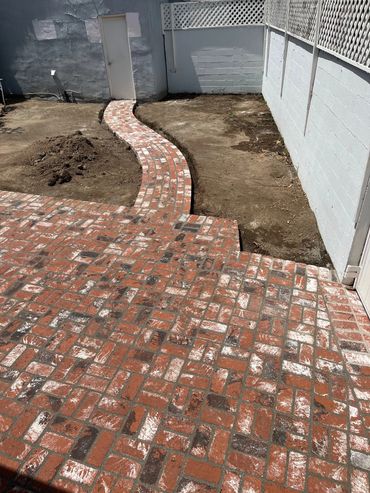A brick walkway in the middle of an empty yard.