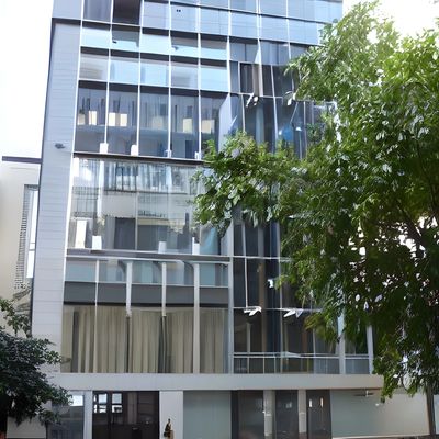Modern glass building with reflective windows and surrounding greenery.