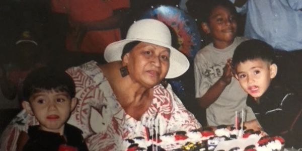 A woman with two boys and a cupcake at a decorated birthday table.