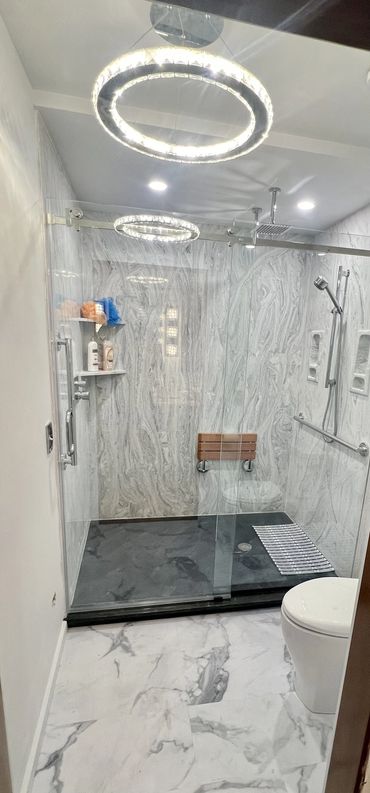 Modern marble bathroom with glass shower and circular ceiling lights.