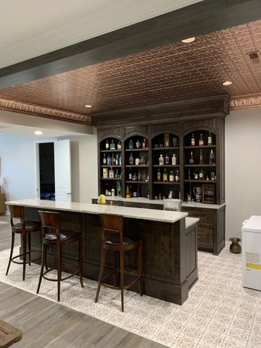 Home bar with wooden cabinets and a patterned copper ceiling.