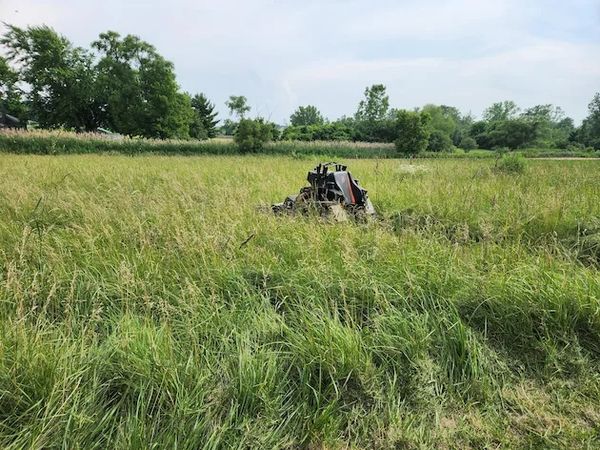 Stand on mower cutting high grass