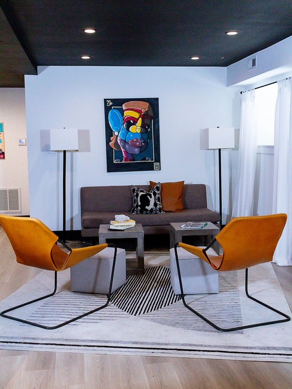 Modern living room with mustard chairs, gray sofa, and colorful artwork.