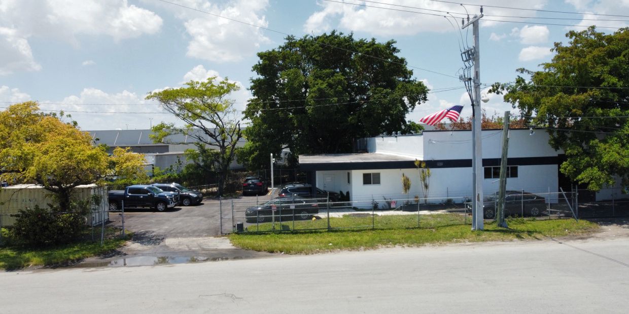Small building with an American flag and several parked cars.