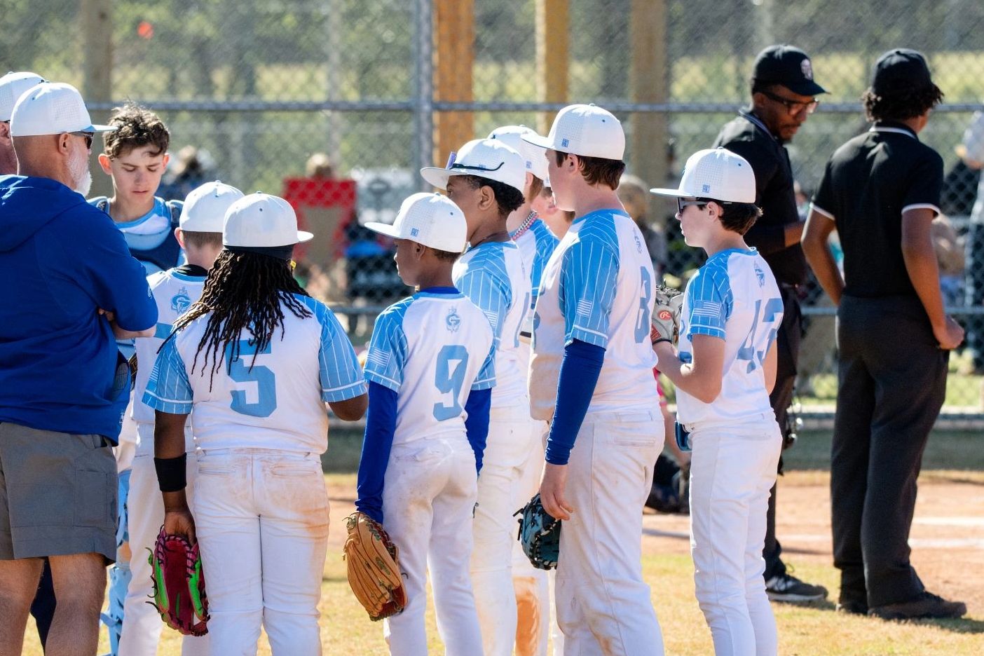 Youth baseball team in white and blue uniforms preparing for a game.