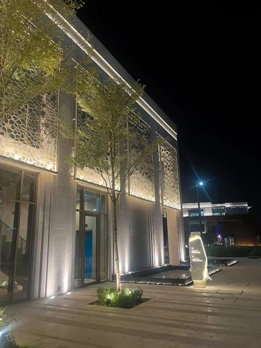 Modern building exterior illuminated at night with decorative metal panels.