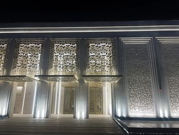Modern building entrance with decorative illuminated panels at night.