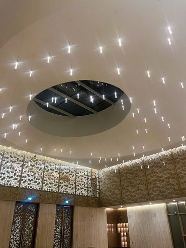 Modern ceiling lights hanging from a circular ceiling with patterned walls.