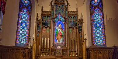 A church altar with stained glass windows and a green altar cloth.
