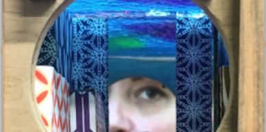 Eye peering through a circular wooden frame with colorful patterned blocks.