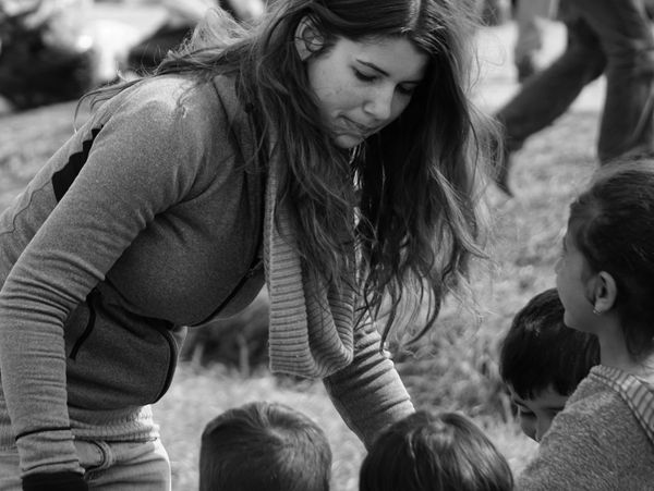 Woman interacts with children outdoors.