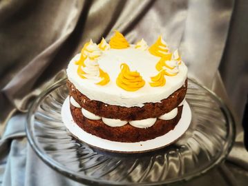 Two-layered cake with white and yellow frosting on glass platter.