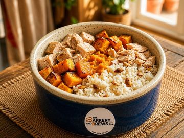 A bowl with roasted sweet potatoes, chicken, rice, and nuts.
