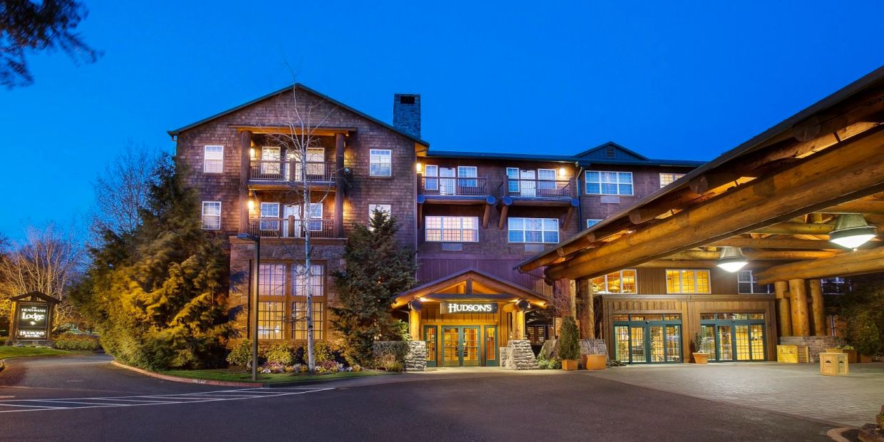 Evening view of a warmly lit lodge with rustic wooden architecture and welcoming entrance.