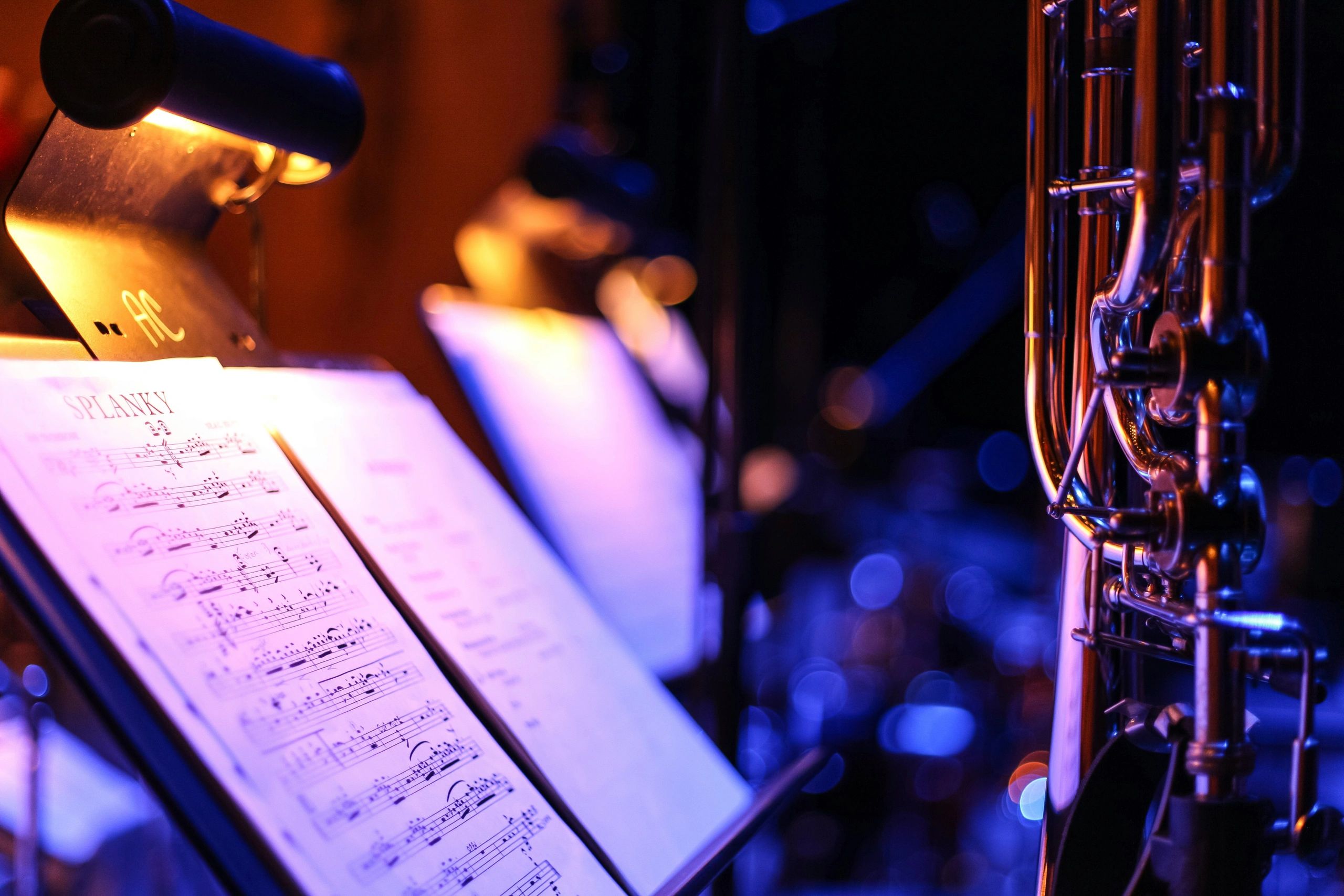 Close-up of sheet music and brass under warm stage lighting, set for film and TV scoring.