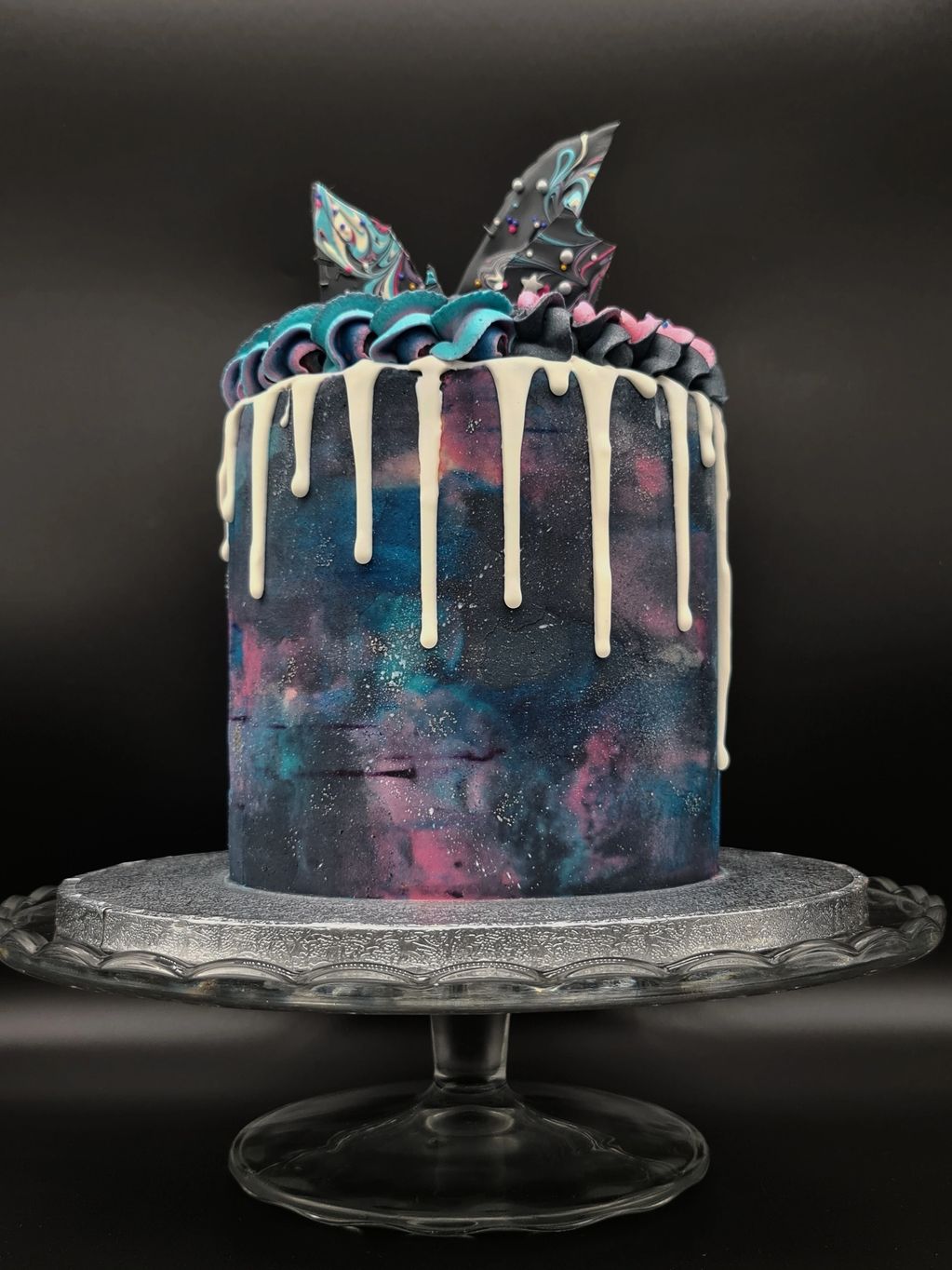 Galaxy cake with a white drip and chocolate shards. Battenberg flavoured cake.