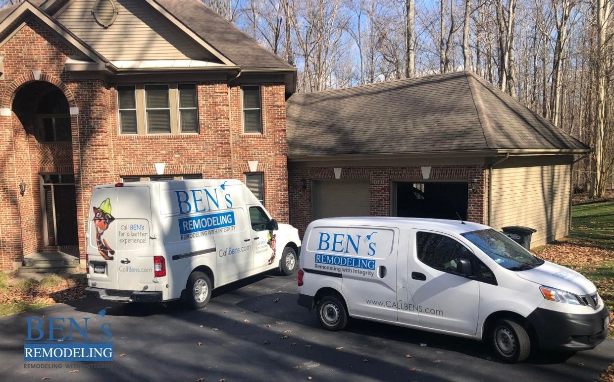 2 large business vans of BEN's Remodeling  on a job site with logos & the giraffe mascot on them